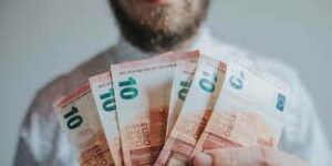 persona che mostra un ventaglio di banconote da 100 euro