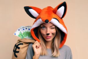 ragazza che fa l'occhiolino vestita da volpe e con un sacco contenente euro sulla schiena